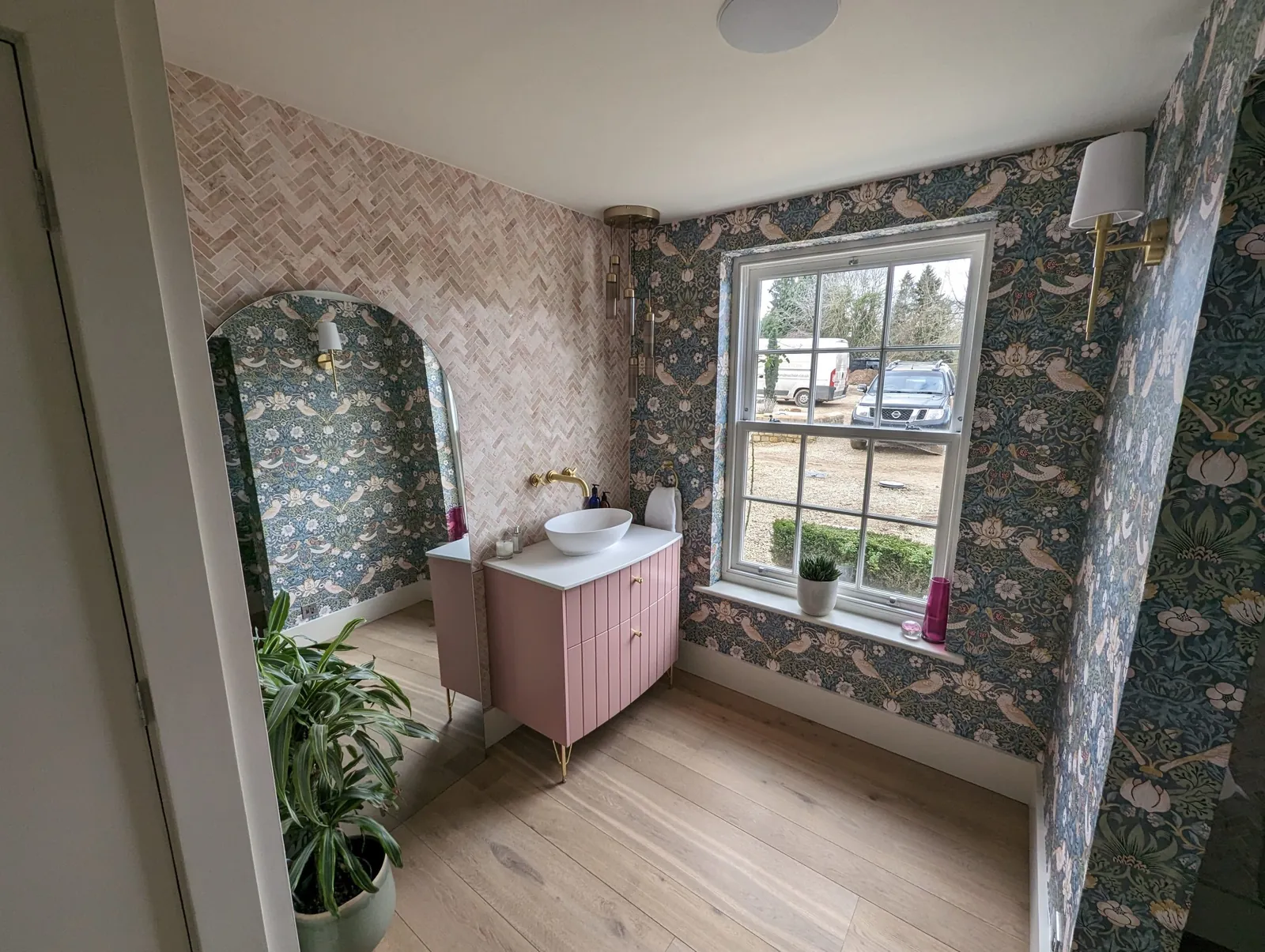 Renovated bathroom with botanical wallpaper and a pink vanity