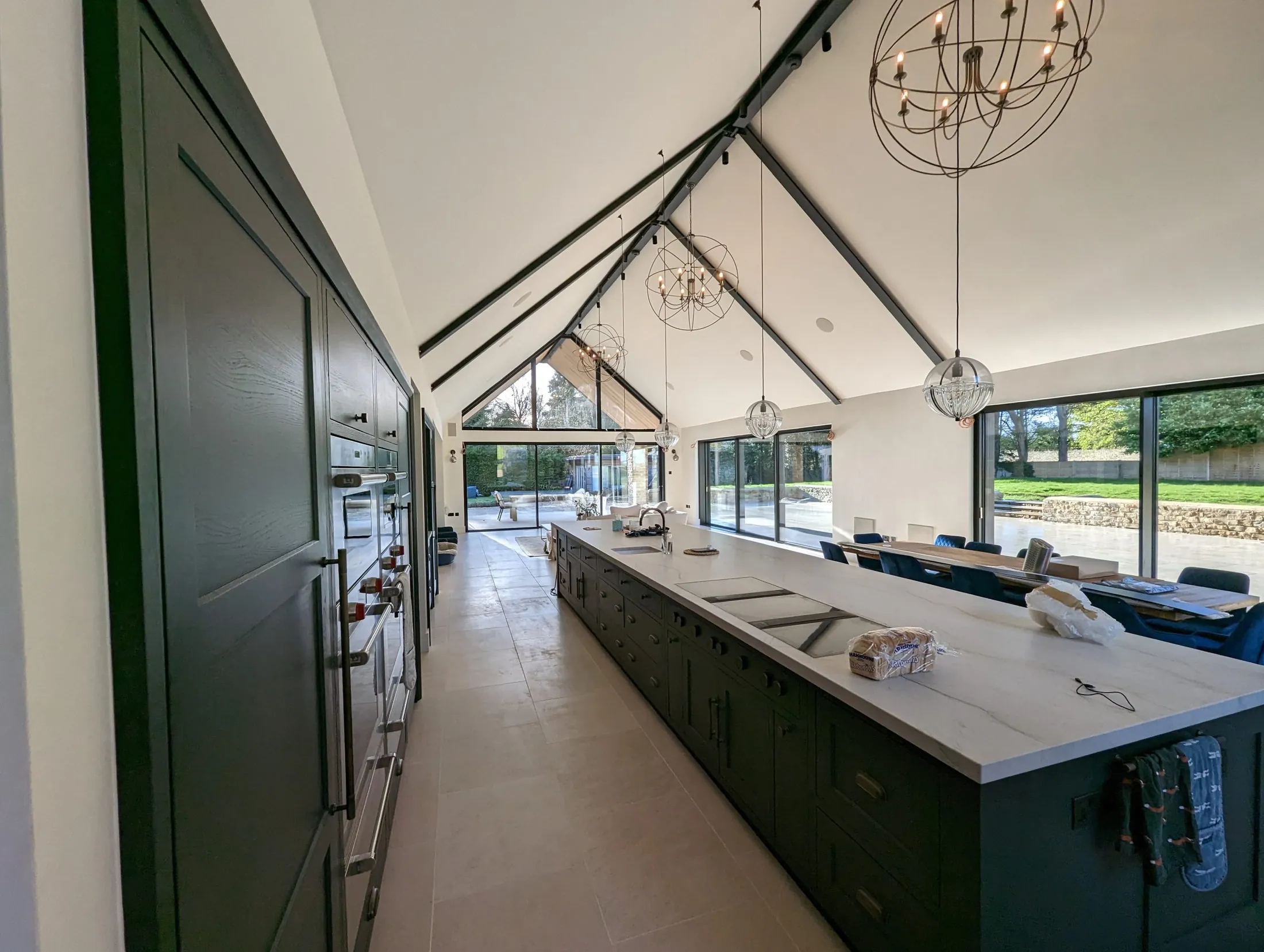 Vaulted open-plan kitchen with a long island and chandeliers
