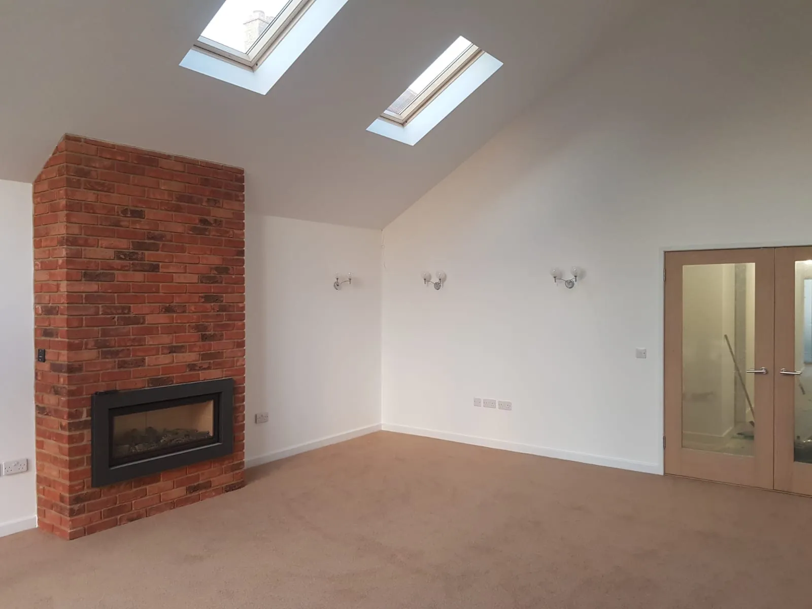 Vaulted living room with a reclaimed brick chimney breast and skylights