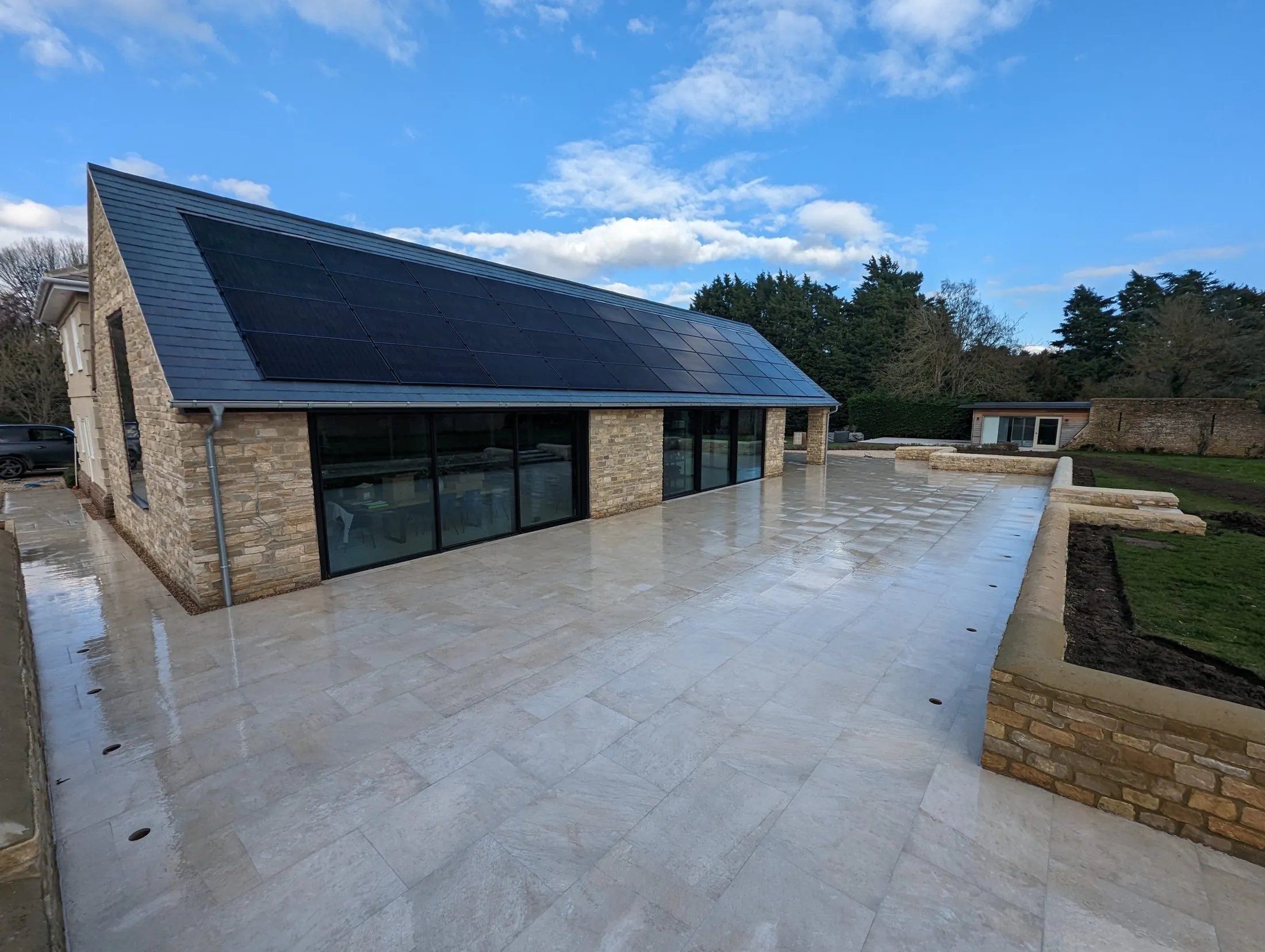 Single-storey stone extension with a slate roof and wide stone terrace